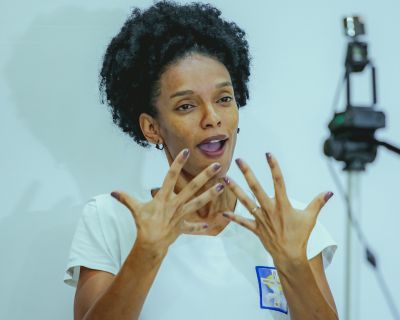 Black woman in white t-shirt interpreting into ASL